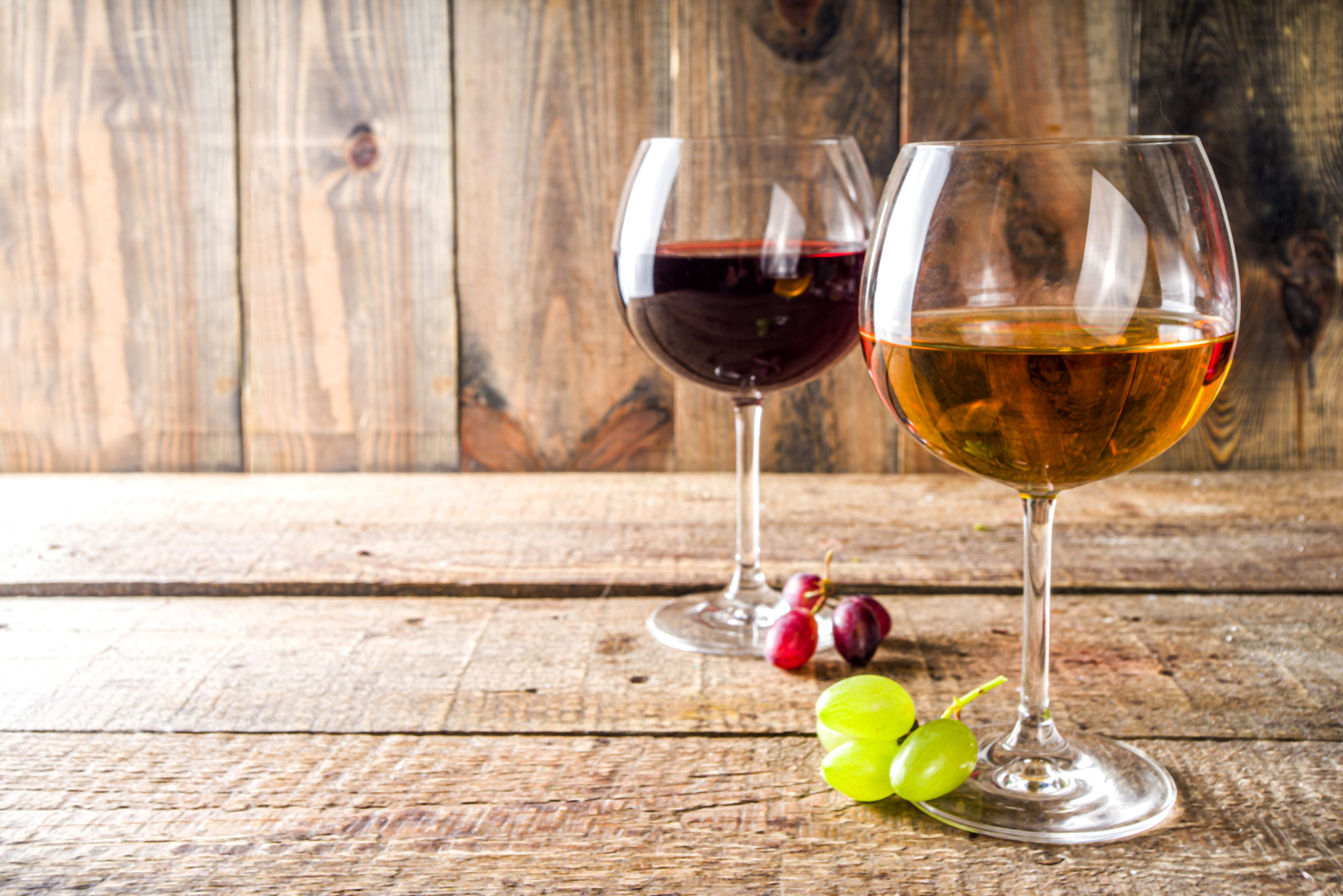 Glasses with wine. Red and white wine in glasses with grape on wooden background copy space